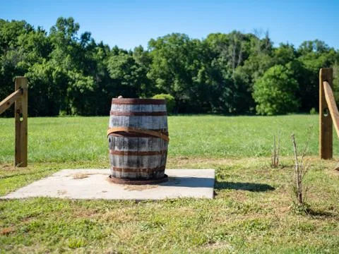 Almost broken barrel sitting in front of field on sunny day Stock Photos