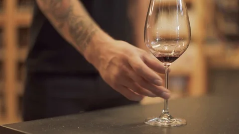 Almost empty glass of red wine is on the desk closeup Male hand takes glass from Stock Footage 99374191