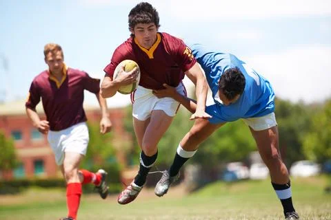 Almost there.... Full length shot of a young rugby player trying to avoid a Stock Photos