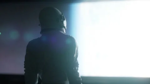 Alone astronaut looking at the huge illuminator of an unknown spaceship interior Stock Footage 154330247