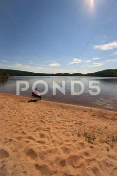 Alone on the beach of a calm wilderness lake Stock Photos