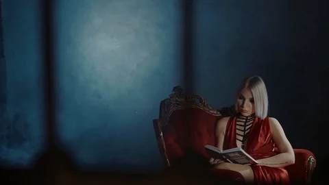 Alone blonde girl is reading book in dark room, male shadow is showing on a wall Video stock 88409090