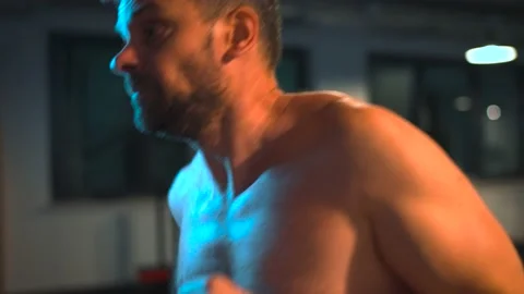 Alone boxer is working out blows on a punching bag in a gym in evening. Stock Footage 209591945