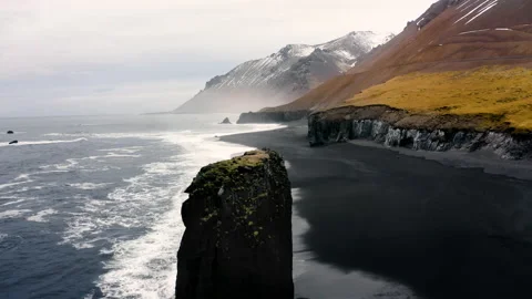 Alone Cliff washed by ocean waves on a black beach in Iceland. Untouched Arctic Stock-Footage 188770787