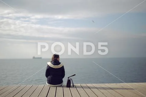Alone Girl waiting for boat on coast. She is refugee and waiting for new life Stock Photos