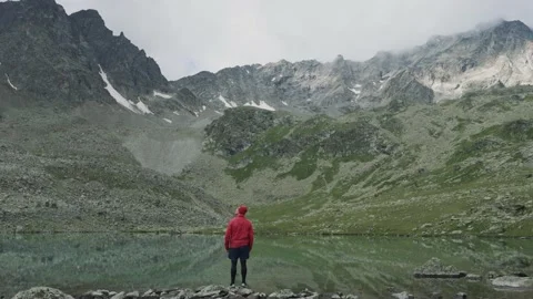 Alone hiker man in red jacket walking among the lake and mountains Stock Footage 137941634