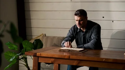 Alone male prayer reading old literature at home. Man in black shirt holding Stock Footage 262485535