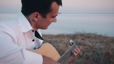 Alone man playing guitar sitting on the coast Stockbeeldmateriaal 161094084