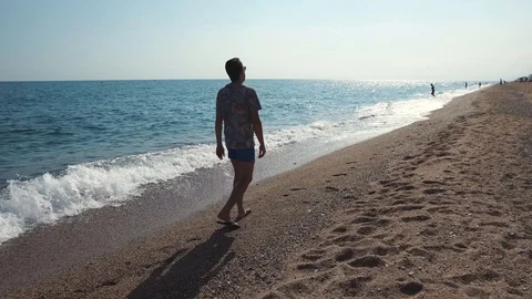 Alone man is strolling on seacoast in summer vacation in daytime Stock Footage 100124341