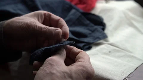 Alone old man hands sew buttons to warm shirt closeup Stock Footage 130693210