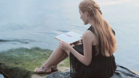 Alone red-haired girl reading book at river 스톡 동영상 65504928
