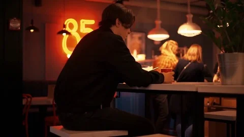 Alone young man typing messages on smartphone in bar in the evening Stock Footage 77168512