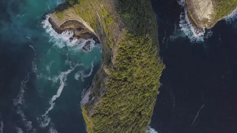 Along the green rock ridge with amazing turquoise ocean waves top down view Stock Footage 101670053