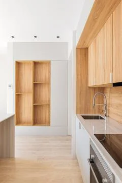 Along the wall is a modern kitchen with light wood cabinets. The marble top has Фото