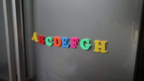 Alphabet magnets are placed onto kitchen fridge by young child's hand Stock Footage 336223510