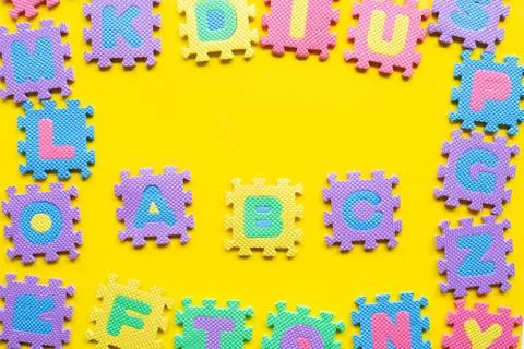 Alphabet puzzle on yellow background. Stock Photos