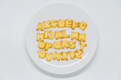Alphabet shape cracker on dish with white background Stock Photos