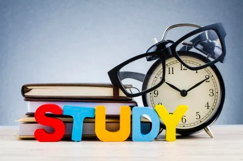 Alphabet word STUDY and stacking book with spectacles on wooden desk over dar Stock Photos