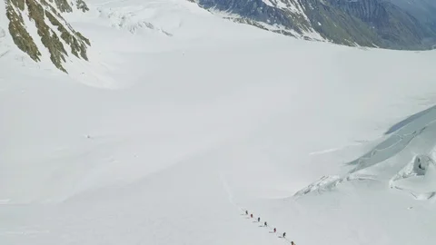 Alpine expedition climbs over broad snow slope, sunny scenic highland landscape Stock Footage 126364236