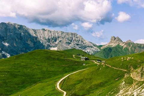 Alpine huts located between the mountains on lush green fields of grass in the D Stock Photos