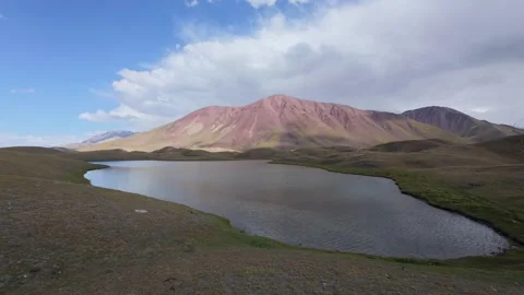 Alpine lake below a red mountain in the Pamir, Alay Valley, Kyrgyzstan Stock Footage 347242889
