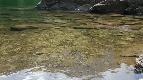 Alpine lake bottom with stones visible through limpid water Stock Footage 166235639