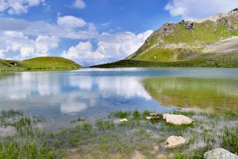Alpine lake in mountain with clouds reflection on the water Stock Photos