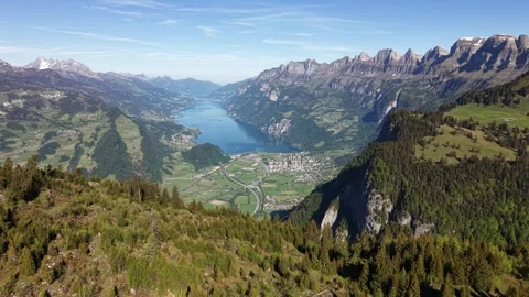 Alpine lake surrounded by mountains valley highway and town Stock Footage 335592420