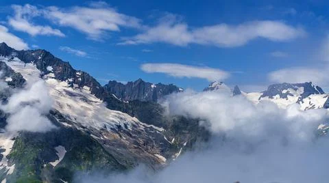 Alpine landscape. High mountains in the clouds. Stock Photos