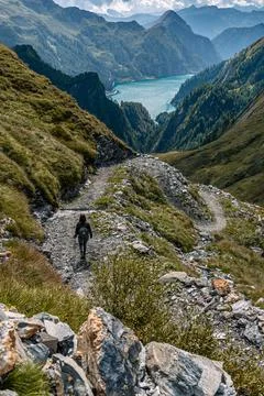 Alpine landscape with a path winding through the mountains and a lake in the Stock Photos