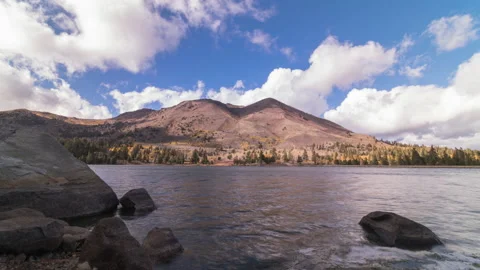 Alpine landscape, timelapse of clouds moving over mountains and lake with rocks Stock Footage 221388678