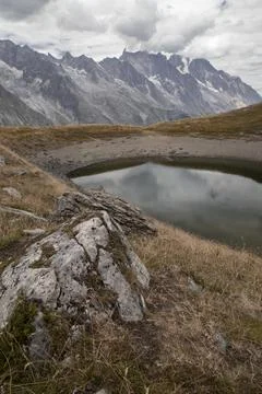 Alpine mountain lake reflecting dramatic sky and rugged peaks Stock Photos