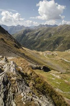 Alpine mountain landscape featuring winding road and buildings Stock Photos