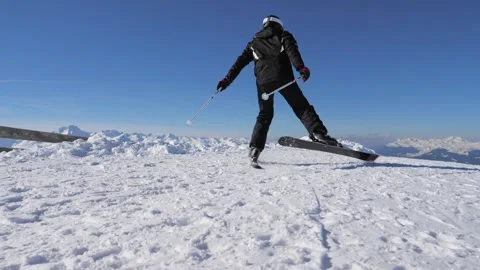 Alpine mountain pinnacle under bright sky with skier prepared to descend Stock Footage 323460879