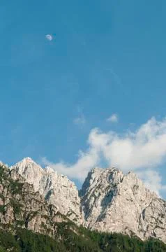 Alpine mountain range with blue sky and a moon Stock Photos
