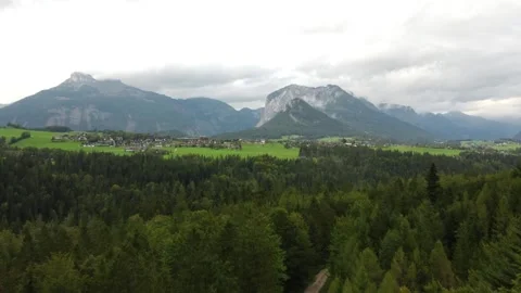The Alpine mountains, hidden behind a soft veil of clouds, rise majestically abo Stock Footage 290077861