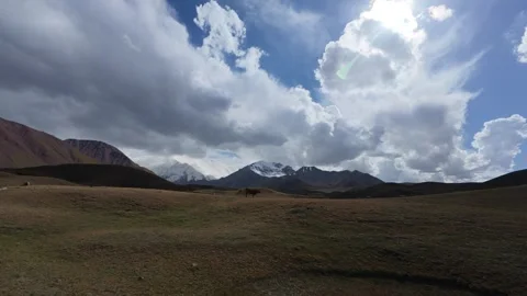 Alpine plateau with dramatic cumulus clouds and a snow peak, Kyrgyzstan Видео 347242887