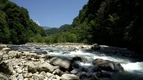 Alpine river. Snow capped mountain peaks and clouds in the background. Summer . Stock Footage 115962906