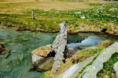 Alpine river stream flowing among alpine meadows of the devero alp on a sunny Stock Photos