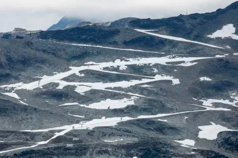 An alpine road covered in snow zig zags up a mountain and leaves a white line, Stock Photos