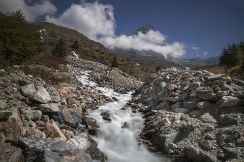 Alpine stream flowing through a rocky mountain landscape Stock Photos