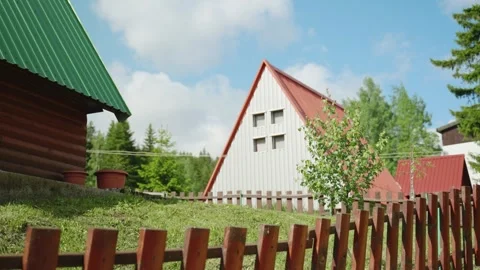 Alpine style cabin chalet or house with fence and green grass during summer Stock Footage 284386336