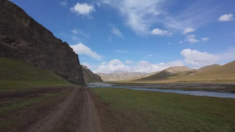 Alpine valley dirt road below jagged peaks, Naryn Region, Kyrgyzstan Stock Footage 347242875