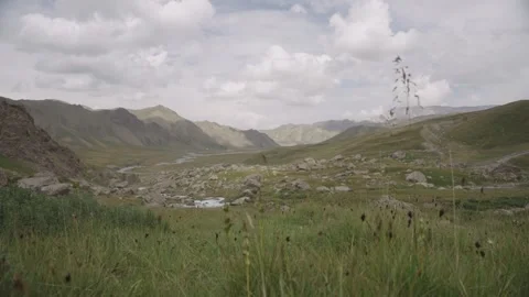 Alpine valley meadow with clouds and mountains, Kel-Suu, Kyrgyzstan Stock Footage 347243034
