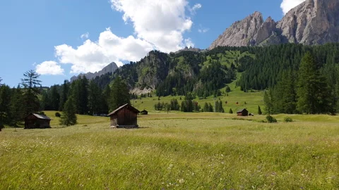 Alpine valley with mountain huts, green meadows and the Dolomites Stock Footage 270423847