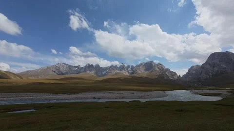 Alpine valley river below jagged peaks and clouds, Naryn Region, Kyrgyzstan Video stock 347242868