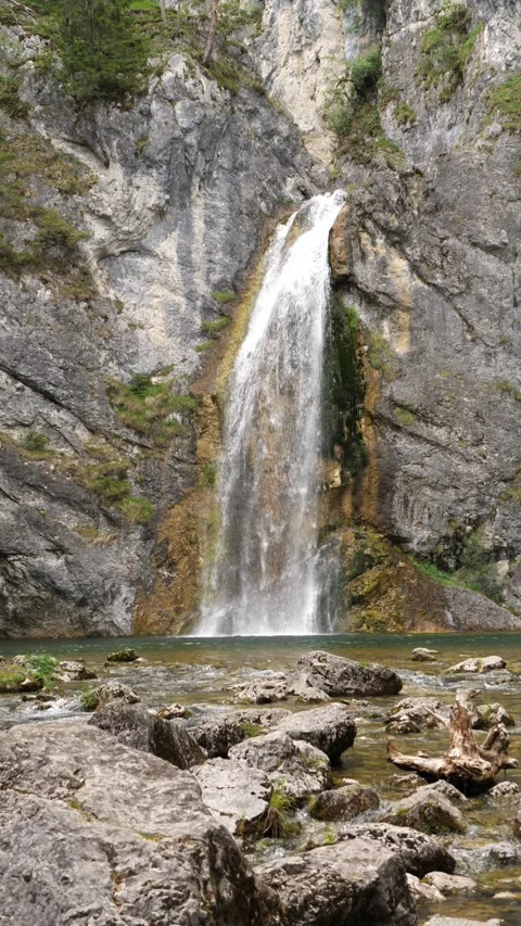 Alpine waterfall cascading down a cliff into a turquoise mountain pool Stock Footage 342520648