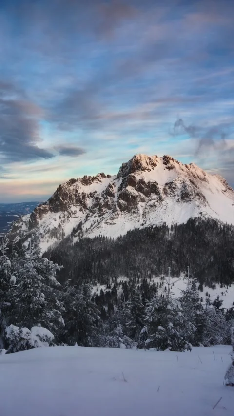 Alpine winter mountain peak with drifting clouds at blue hour before sunrise Stock Footage 315529839