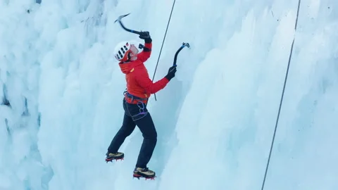 Alpinist man climbing on a frozen waterfall Stock Footage 157779016