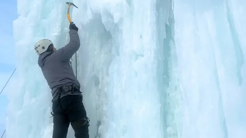 Alpinist man with ice tools axe climbing a large wall of ice Stock Footage 120459740